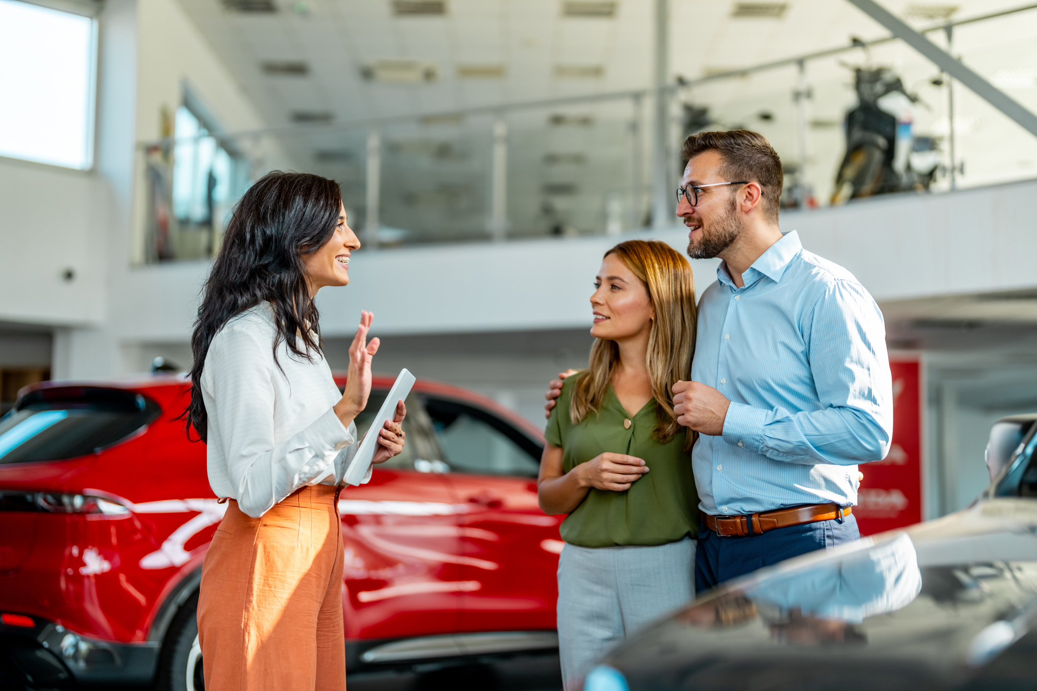 Three people with a Chevrolet salesperson at a dealership, on the FAQ tariffs page.